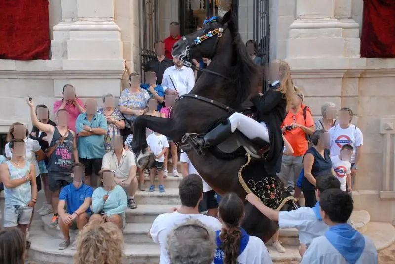fiestas de Menorca en el jaleo donde aparece chica subida a un caballo realizando bailes y cabriolas rodeada de gente