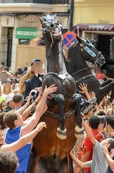 fiestas de Menorca en el jaleo donde aparece chica subida a un caballo realizando bailes y cabriolas rodeada de gente