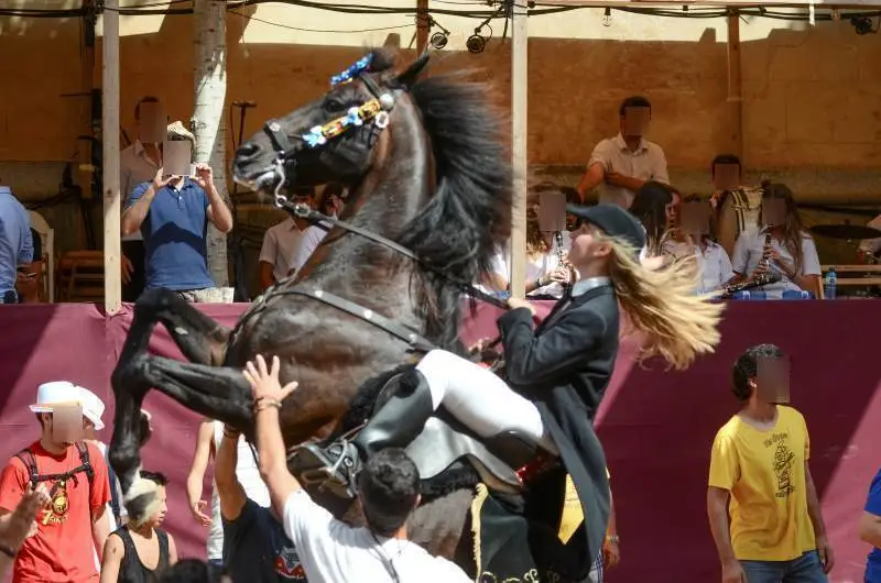 fiestas de Menorca en el jaleo donde aparece chica subida a un caballo realizando bailes y cabriolas rodeada de gente