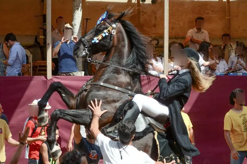 fiestas de Menorca en el jaleo donde aparece chica subida a un caballo realizando bailes y cabriolas rodeada de gente