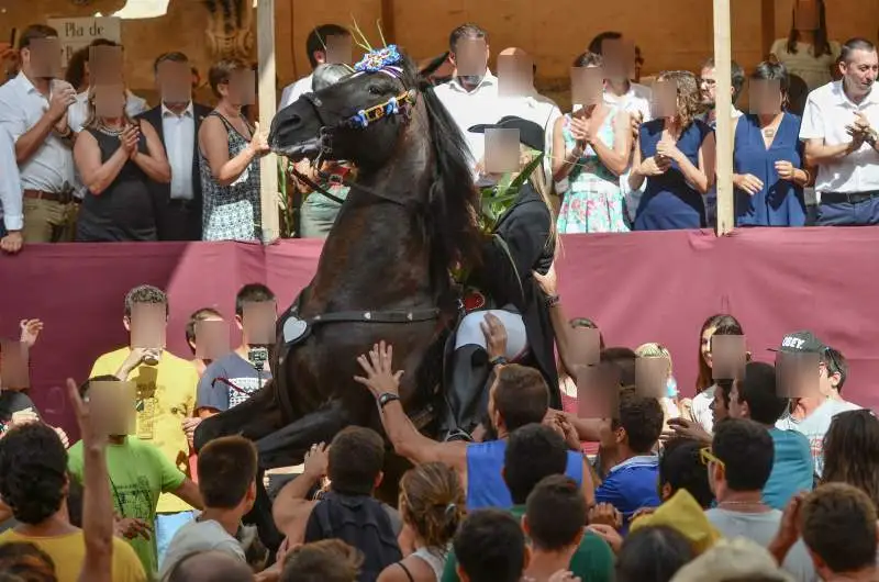 fiestas de Menorca en el jaleo donde aparece chica subida a un caballo realizando bailes y cabriolas rodeada de gente