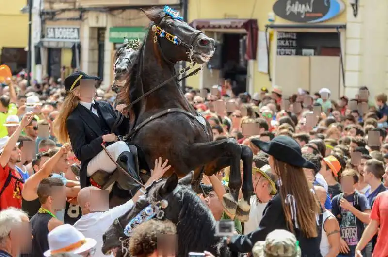 fiestas de Menorca en el jaleo donde aparece chica subida a un caballo realizando bailes y cabriolas rodeada de gente