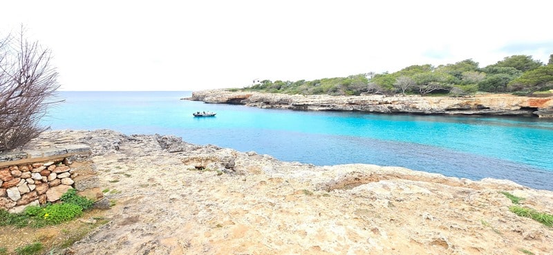 Playa de Cala Blanca con zona urbana al fondo en Menorca