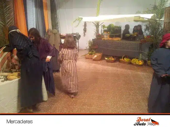 Mercaderes en el nacimiento viviente de Menorca, escena navideña tradicional con puestos y vecinos caracterizados.